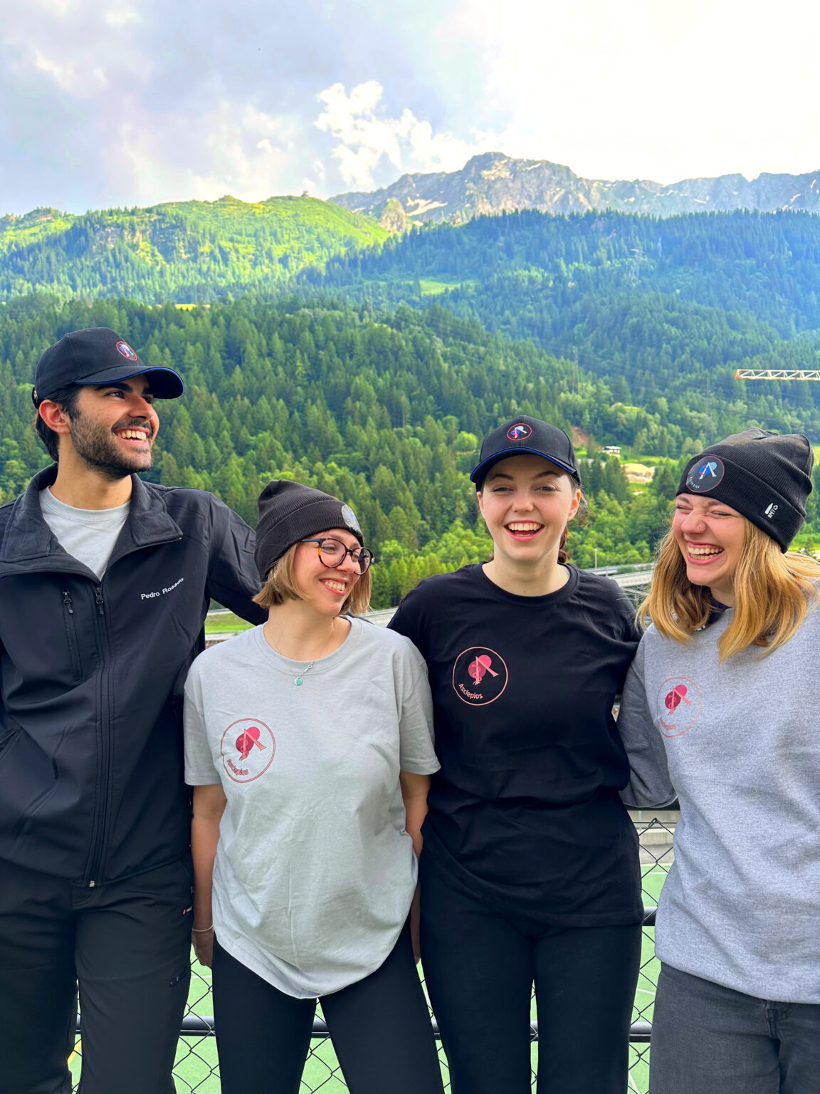 Four members of the Asclepios crew in branded caps, beanies, t-shirts and sweatshirts
